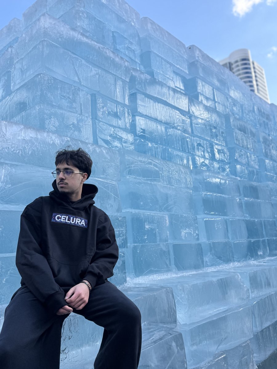 Huzaifa wearing a Celura hoodie beside a wall of ice